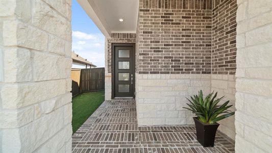 Approaching the front door you will see the warm dark brick with contrasting light stone! The spacious covered porch is completed with a modern front door, overhead led lighting, and brick pavers.