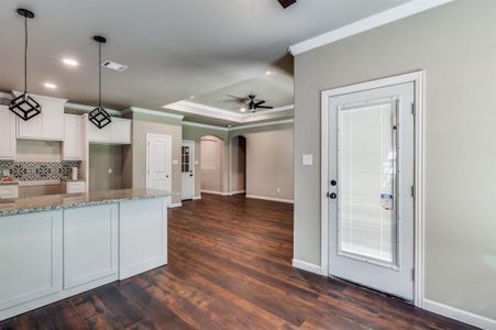 Kitchen featuring dark hardwood / wood-style flooring, pendant lighting, backsplash, white cabinetry, and ceiling fan