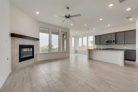 Kitchen featuring an island with sink, light wood-type flooring, a fireplace, and ceiling fan