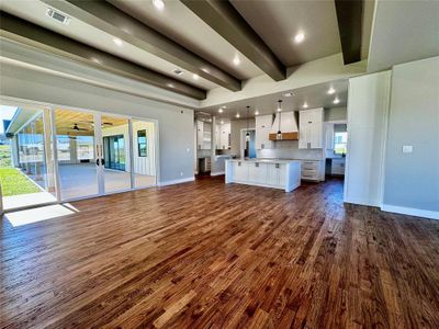 Unfurnished living room featuring dark hardwood / wood-style flooring and beamed ceiling