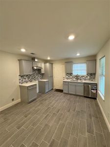 Kitchen with dishwashing machine, dark wood-type flooring, and gray cabinets