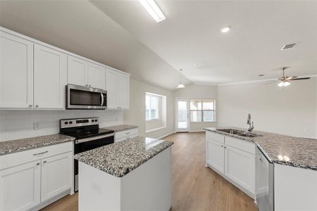 Kitchen with vaulted ceiling, stainless steel appliances, ceiling fan, a kitchen island with sink, and sink