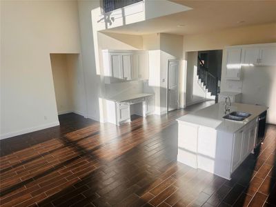 Kitchen featuring sink, an island with sink, white cabinetry, a towering ceiling, and dark hardwood / wood-style flooring