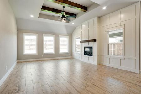 Unfurnished living room with beamed ceiling, ceiling fan, a large fireplace, and light hardwood / wood-style floors