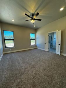 Carpeted empty room with ceiling fan and a textured ceiling