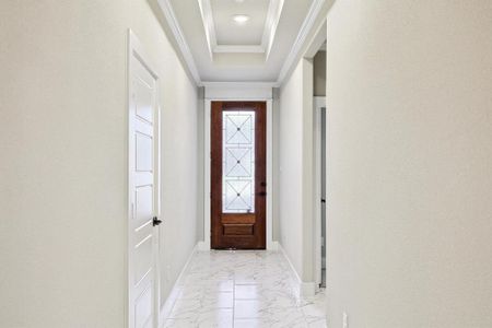 Entryway featuring light tile floors, ornamental molding, and a raised ceiling