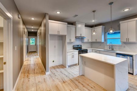 Kitchen with dishwasher, light hardwood / wood-style floors, decorative backsplash, black electric range, and sink