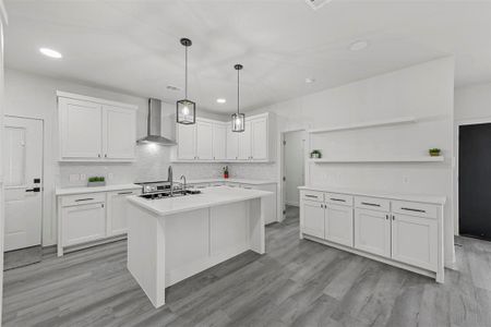 Kitchen featuring an island with sink, wall chimney exhaust hood, light hardwood / wood-style floors, and white cabinets