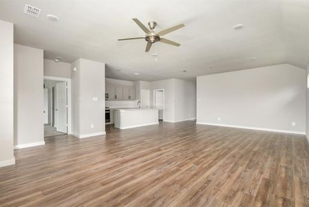 Unfurnished living room featuring lofted ceiling, ceiling fan, and light wood-type flooring