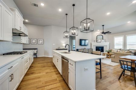 Kitchen featuring an island, lantern pendant lighting, stainless steel appliances, and white cabinetry