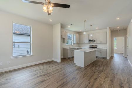 Kitchen with a kitchen island, appliances with stainless steel finishes, sink, hardwood / wood-style flooring, and ceiling fan