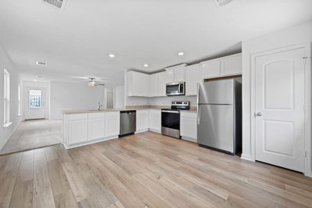 Kitchen includes granite countertops, luxury vinyl plank flooring, 36” upper cabinets with crown molding, a full suite of stainless-steel Whirlpool appliances – including refrigerator with ice maker, recessed lighting, and a large single basin sink.