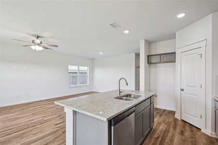 Kitchen with sink, hardwood / wood-style flooring, stainless steel dishwasher, ceiling fan, and a center island with sink