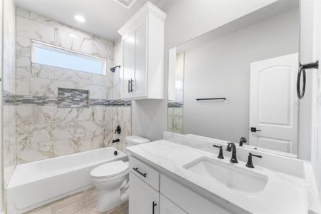 Full bathroom featuring hardwood / wood-style floors, vanity, toilet, and tiled shower / bath