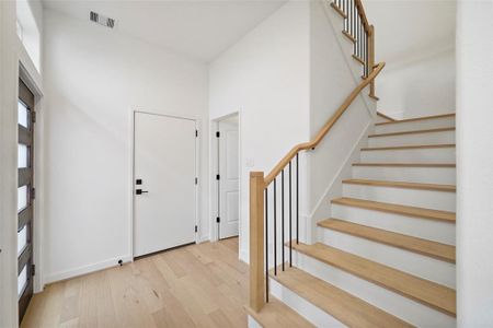 Sleek white oak flooring complements the modern, white-riser staircase.