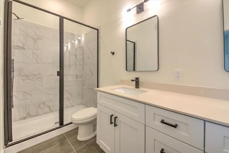 Primary bathroom with large shower, ceramic tile flooring and wall tile, double-sinks