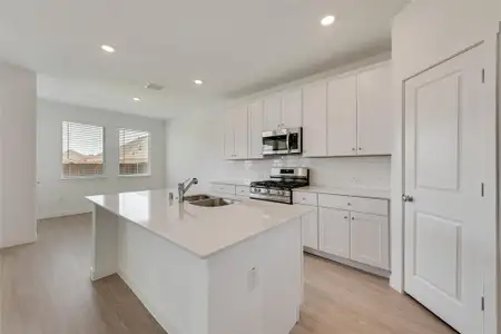 Kitchen with an island with sink, sink, stainless steel appliances, and white cabinets