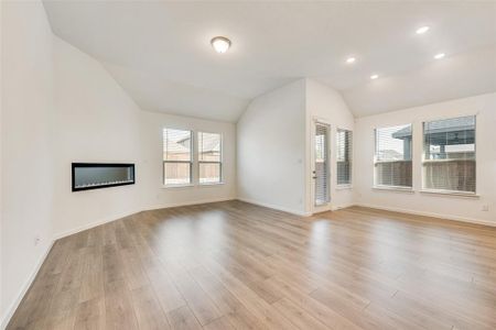 Unfurnished living room with lofted ceiling, plenty of natural light, and light hardwood / wood-style flooring