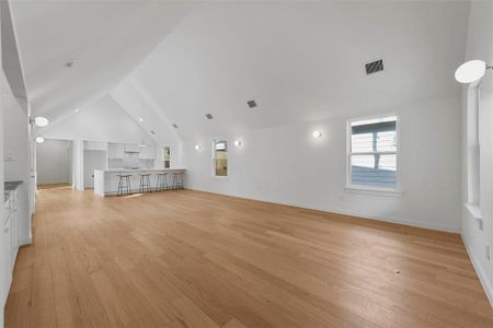 Unfurnished living room with light wood-type flooring and vaulted ceiling