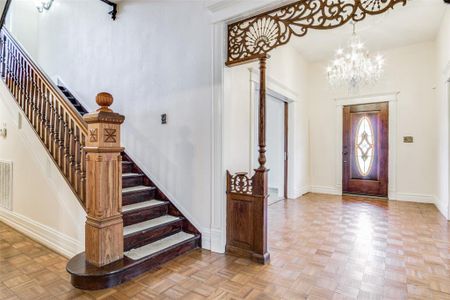 Entrance foyer featuring light parquet floors, a notable chandelier, and a towering ceiling