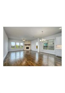 Unfurnished living room featuring ceiling fan with notable chandelier, dark hardwood / wood-style flooring, and a stone fireplace