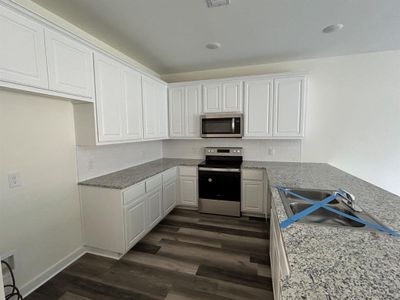 Kitchen with stainless steel appliances, dark hardwood / wood-style flooring, and backsplash
