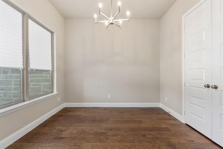 Unfurnished dining area with an inviting chandelier and dark hardwood / wood-style floors