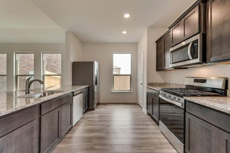 Kitchen featuring light hardwood / wood-style flooring, stainless steel appliances, light stone counters, and a wealth of natural light