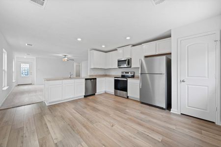 Kitchen includes granite countertops, luxury vinyl plank flooring, 36” upper cabinets with crown molding, a full suite of stainless-steel Whirlpool appliances – including refrigerator with ice maker, recessed lighting, and a large single basin sink.