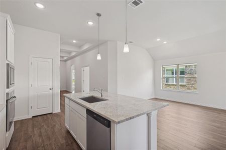 Kitchen with white cabinetry, appliances with stainless steel finishes, wood-type flooring, and a kitchen island with sink