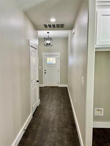 Doorway with dark hardwood / wood-style floors and an inviting chandelier