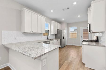With its clean lines and minimalist aesthetic, the large kitchen exudes effortless chic, showcasing the crisp contrast between the white cabinets, sleek stainless-steel appliances, and luxurious granite countertops for a sophisticated yet approachable look.