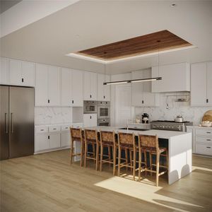 Kitchen featuring appliances with stainless steel finishes, light hardwood / wood-style floors, an island with sink, a breakfast bar, and a tray ceiling