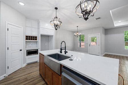 Kitchen with a kitchen island with sink, white cabinetry, a chandelier, and sink