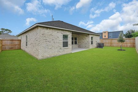 Features a spacious backyard with a lush lawn, privacy fencing, a concrete patio area, and a youthful tree, offering potential for outdoor living and landscaping.