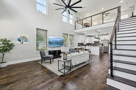 Living room with a high ceiling, dark hardwood / wood-style flooring, and ceiling fan