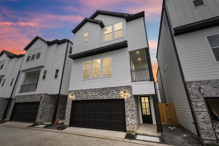 Modern 3 level home with a sleek design, featuring a two-car garage, balcony, and large windows, captured at dusk under a vibrant sky.