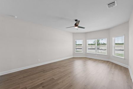 The master bedroom featuring bay windows, LVP flooring, and a ceiling fan.