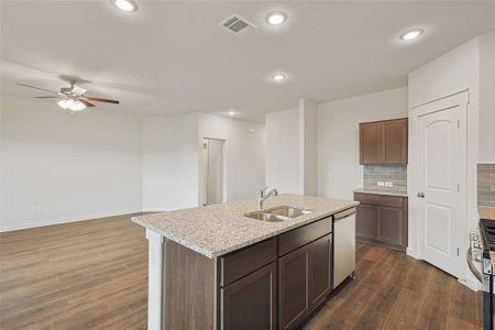 Kitchen featuring sink, dishwasher, backsplash, dark hardwood / wood-style floors, and a kitchen island with sink