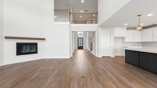 Unfurnished living room with light hardwood / wood-style flooring and a towering ceiling