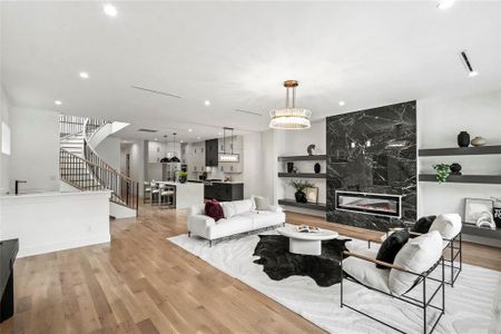 Living room with light hardwood / wood-style floors, a notable chandelier, and a high end fireplace