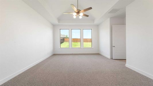 Unfurnished room featuring light colored carpet, a tray ceiling, and ceiling fan