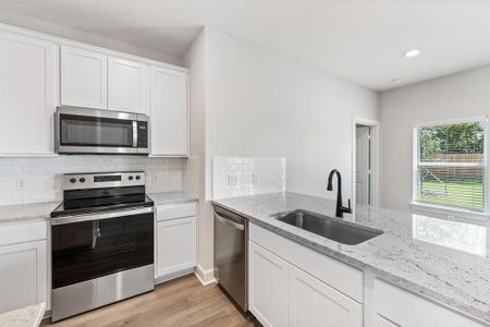 Kitchen featuring white cabinetry, new Whirlpool appliances, light wood-type flooring, sink, and backsplash