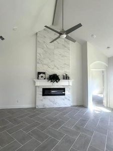 Unfurnished living room featuring ceiling fan, tile walls, and a high end fireplace