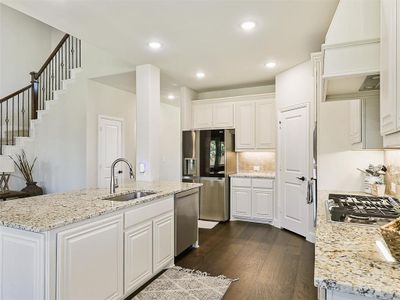 Kitchen featuring custom range hood, sink, white cabinets, appliances with stainless steel finishes, and dark hardwood / wood-style flooring