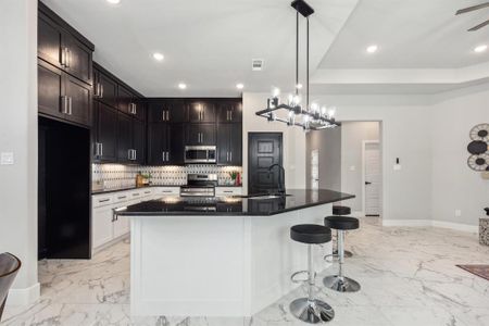 Kitchen with pendant lighting, stainless steel appliances, a kitchen island with sink, and sink