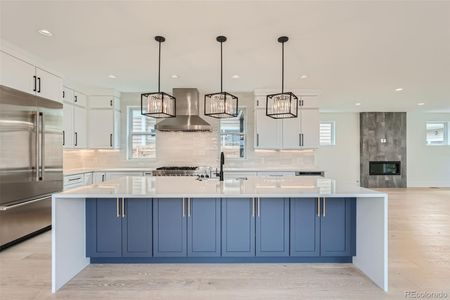 Chef's kitchen showcasing a massive quartz waterfall island, complemented by sleek quartz countertops, undercabinet lighting, stainless steel refrigerator/freezer, six-burner gas range, built-in hood vent, dishwasher, and microwave.