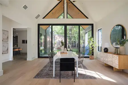 Dining area with light hardwood / wood-style floors and high vaulted ceiling
