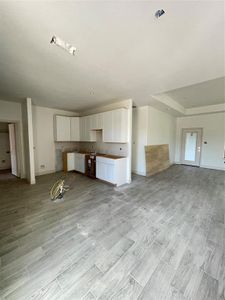 Unfurnished living room with a raised ceiling and light hardwood / wood-style flooring
