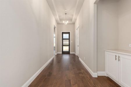 Hallway with dark hardwood / wood-style flooring and a chandelier